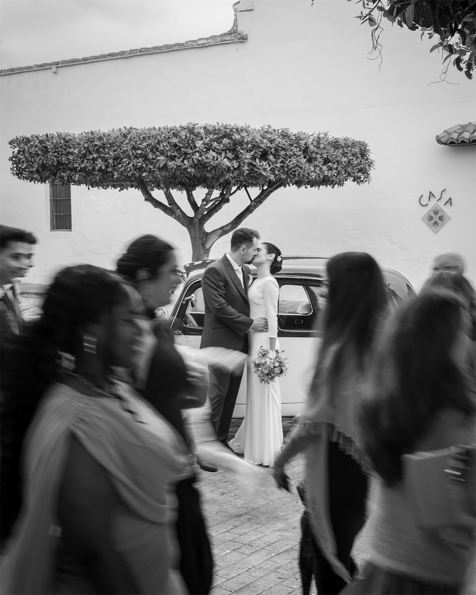 recién casados besándose junto al coche clásico